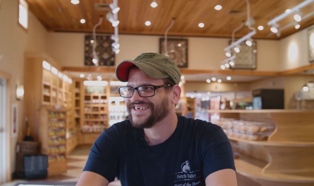 Man sits in bakery smiling.